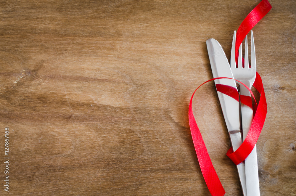 Fototapeta premium Cutlery Decorated with Red Ribbon on Wooden Background.