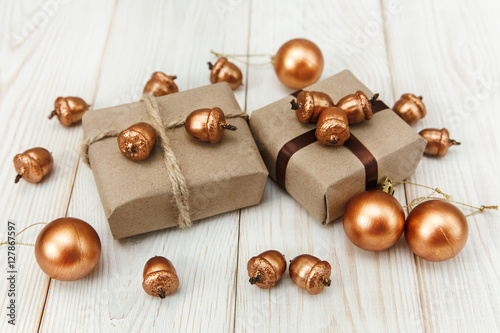 Christmas composition.Present boxes with twine and craft paper,golden acorns and balls.White wooden table.