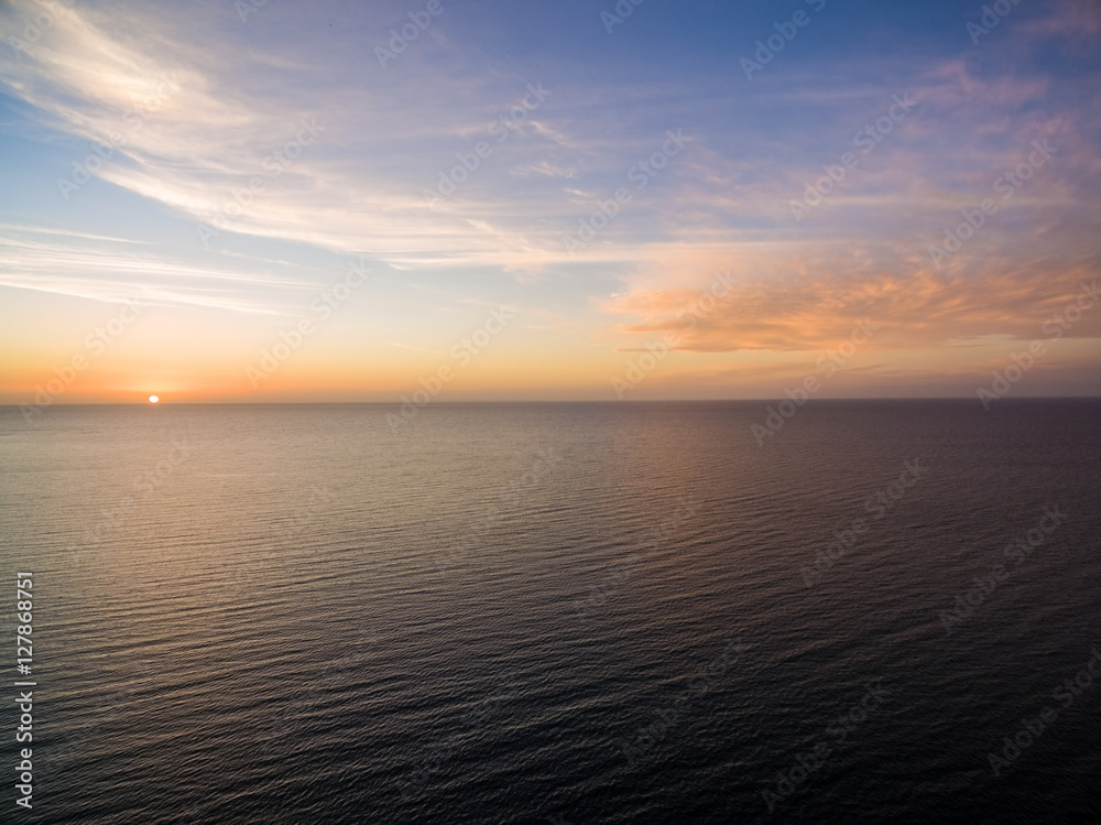 Aerial view of sun setting over ocean. Nothing but skies and water. Beautiful tranquil scene