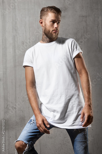 Bearded man in white t-shirt standing on the cement wall background © deniskomarov