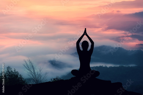 Silhouette of woman practicing yoga at sunrise