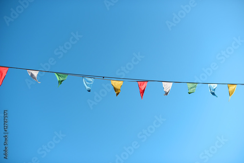 Guirnaldas de fiesta coloridas colgando en la calle en un día soleado con un cielo azul despejado