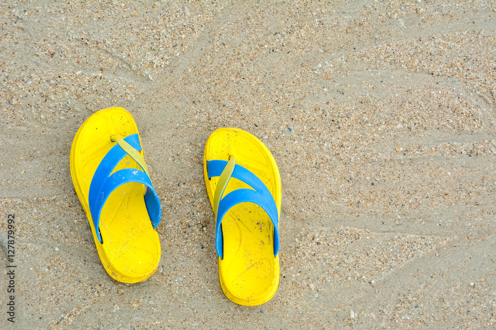 Fototapeta premium Yellow sandals on sandy beach