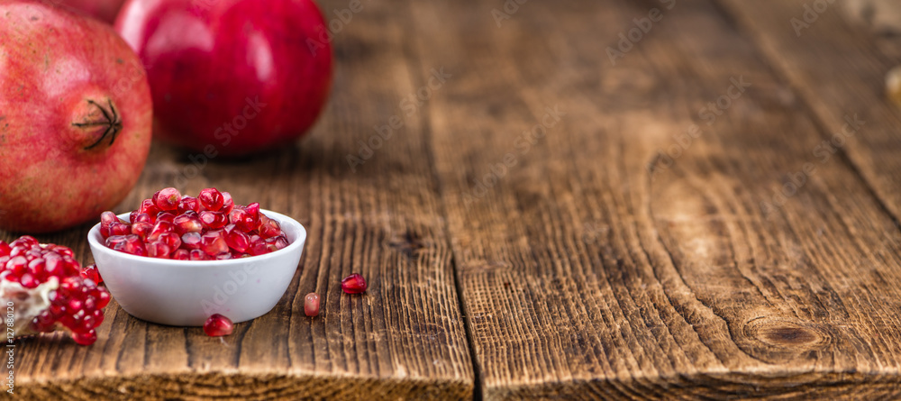 Pomegranate seeds on wooden background (selective focus)
