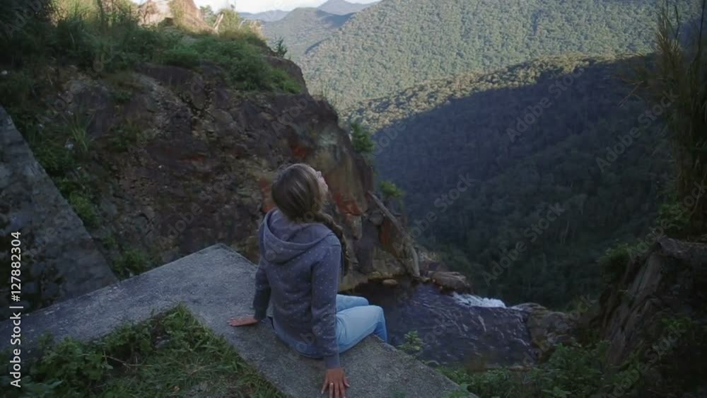 Young woman sitting on the edge of a rocky canyon above the river mountains vietnam Young woman sitting on the edge of a rocky canyon above the river mountains vietnam