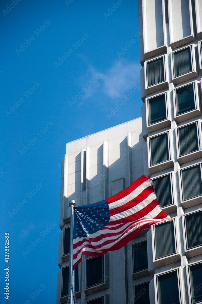Fototapeta premium American Flag in front of Urban High Rise Building