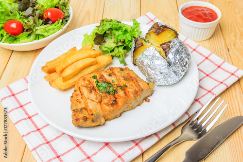 Grilled meat steak serve with tomato sauce, Mashed Potatoes, french fries and vegetable salad, isolated on wooden background, Closed up