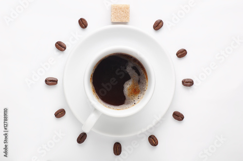 Coffee cup and coffee beans with cane sugar cube against white background forming clock dial viewed from top