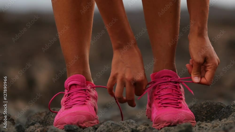 Running woman tying shoe laces going running - girl trail runner. Closeup of female legs and running shoes in action. Girl athlete fitness runner running fast outside in trail running shoes. 59.94 FPS