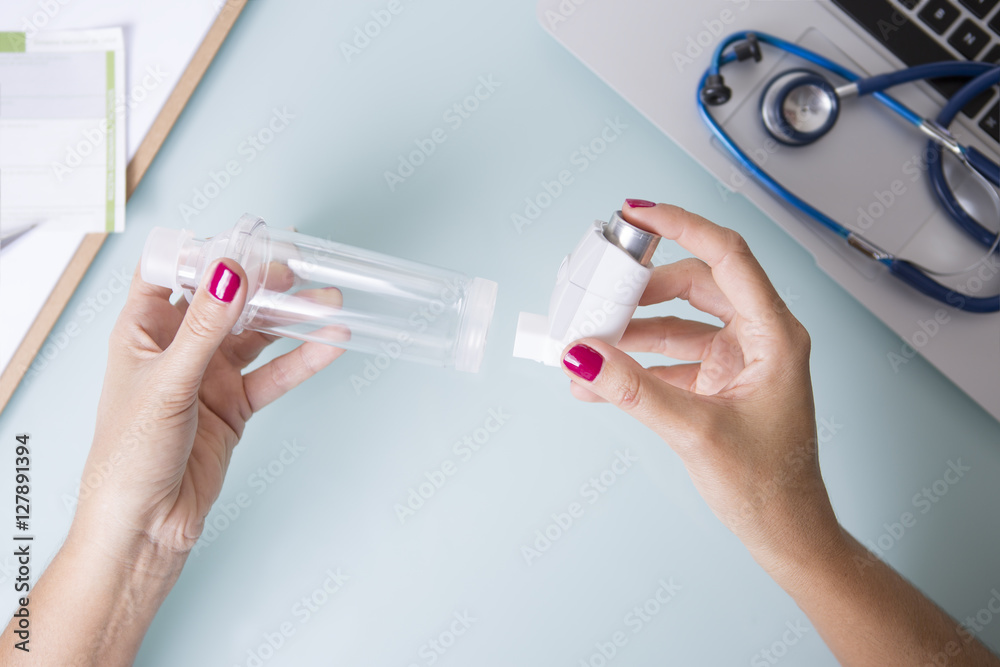 Female hands inserting an aerosol inhaler into a space chamber