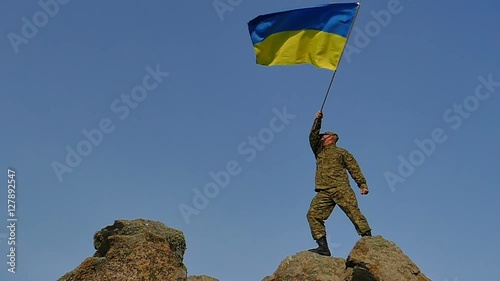 Soldier  waves Ukrainian Flag on mountain top, in Slow Motion 