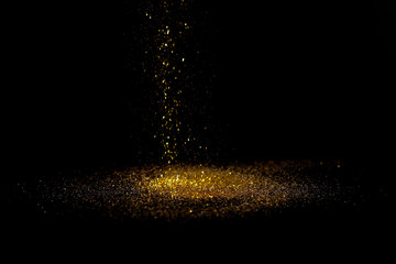 Sprinkle gold dust on a black background with copy space.