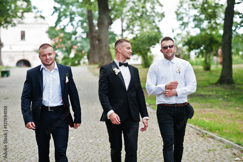 Personable groom with best mans or groomsman posed on park at we