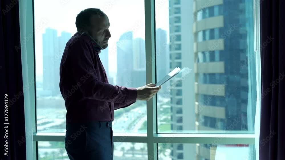 Angry businessman with documents talking on cellphone standing by window in office
Angry businessman with documents talking on cellphone standing by window in office