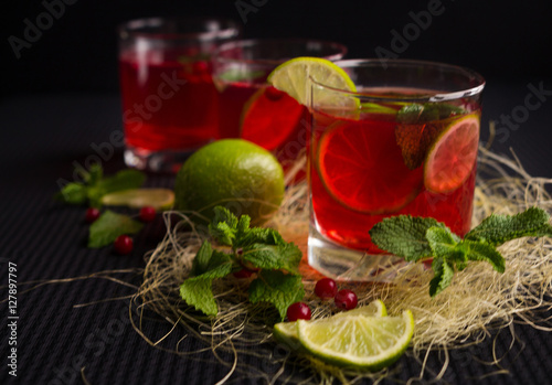 Refreshing drink with lime, mint and cranberries on a dark background