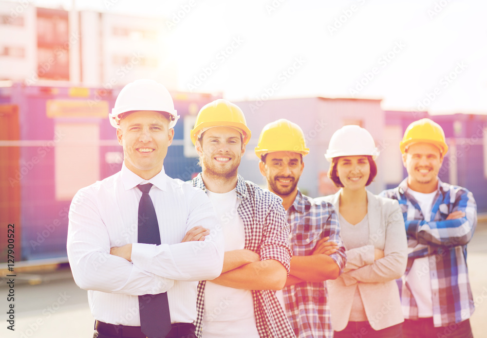 group of smiling builders in hardhats outdoors group of smiling builders in hardhats outdoors
