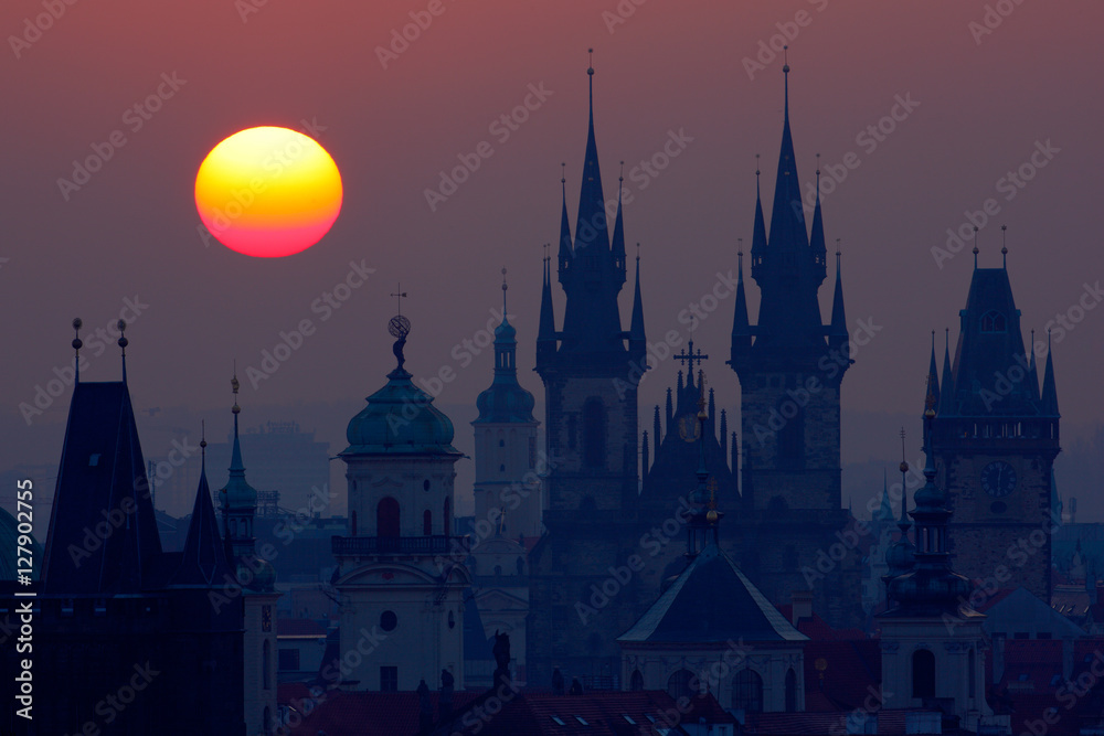 Beautiful detailed sunrise view of Prague church towers. Early morning colours with old town. Twilight in historical city.  Magical picture of tower with orange sun in Prague, Czech Republic, Europe.