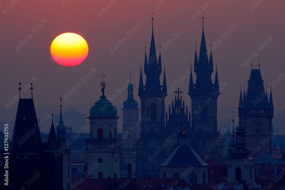 Fototapeta premium Beautiful detailed sunrise view of Prague church towers. Early morning colours with old town. Twilight in historical city. Magical picture of tower with orange sun in Prague, Czech Republic, Europe.