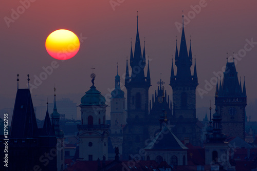 Beautiful detailed sunrise view of Prague church towers. Early morning colours with old town. Twilight in historical city. Magical picture of tower with orange sun in Prague, Czech Republic, Europe.