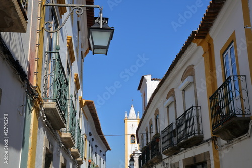 EVORA, PORTUGAL: typical narrow street with white houses and the church of Sao Mamede in the background