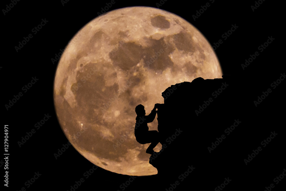 Silhouette Man climbing on a cliff with full moon