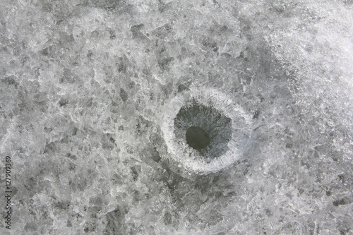 Hole for subglacial fishing on a river surface