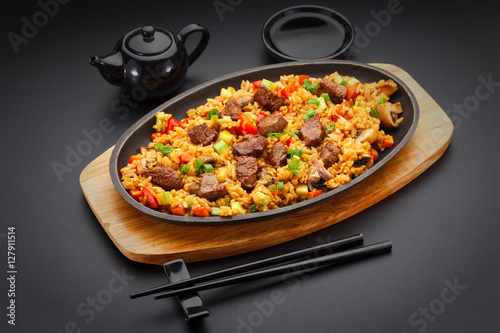Japanese cuisine. Rice with veal over black background.