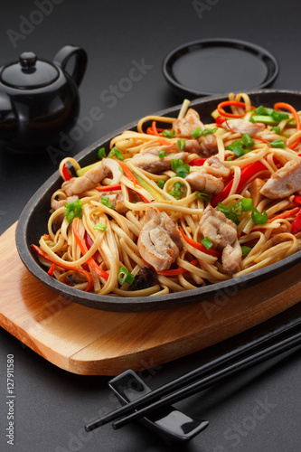 Asia food. Udon noodles with chicken on the black table.