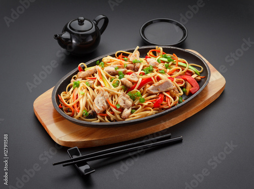 Asia food. Udon noodles with chicken on the black table.