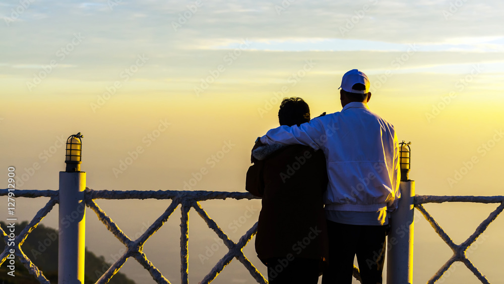 Happy senior couple watching sunrise over the mountain in winter Happy senior couple watching sunrise over the mountain in winter