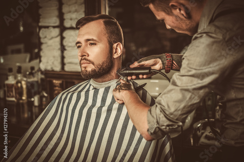 Confident man visiting hairstylist in barber shop.