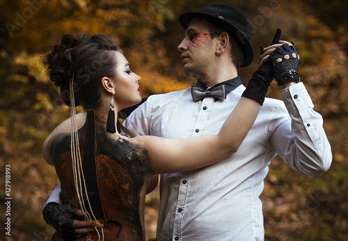 Couple in tango pose imitating music performance on woman's back with painted violin.