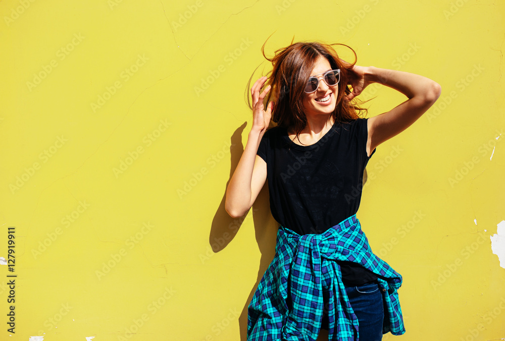 Brunette girl in rock black style, standing against yellow wall outdoors in the city street Brunette girl in rock black style, standing against yellow wall outdoors in the city street