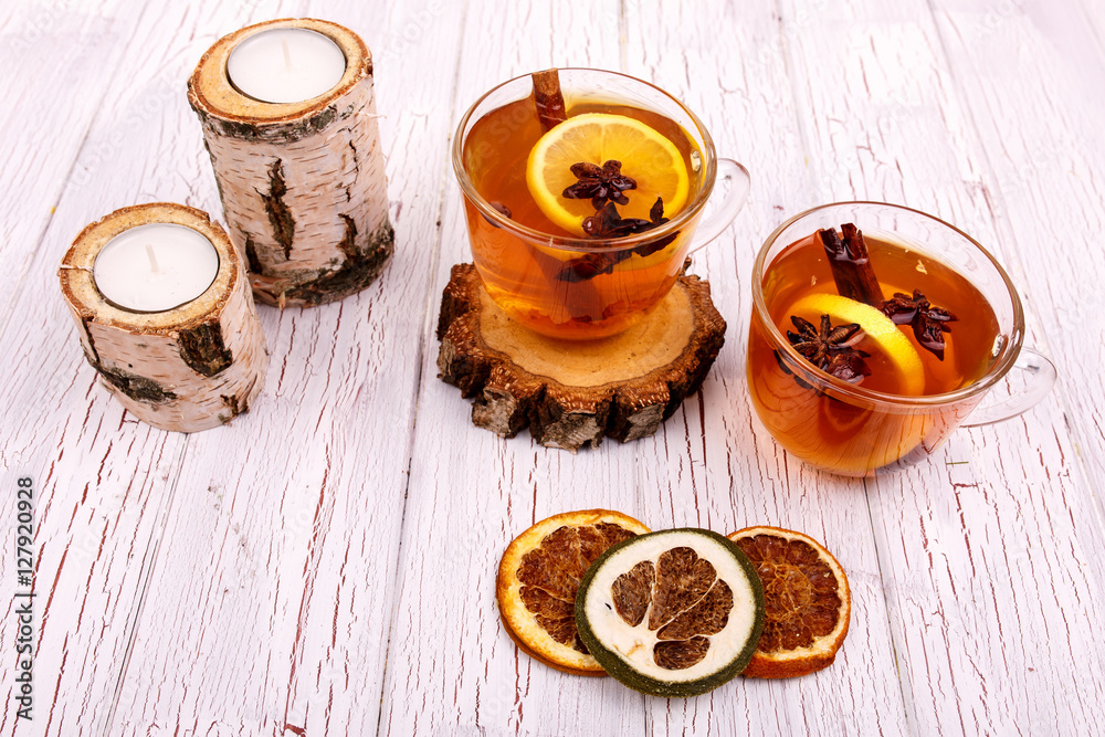 Cup of tea with cinnamon, lemon and other seasonings stands on w Cup of tea with cinnamon, lemon and other seasonings stands on w