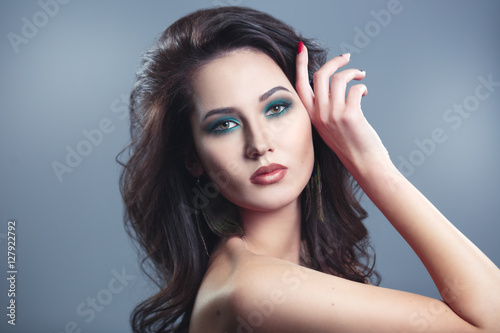 Beauty portrait of a beautiful brunette with green eye make-up on a gray background.