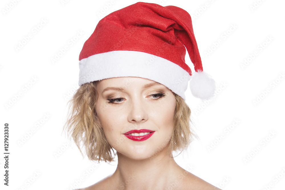 Funny young girl in the hat of Santa Claus holding Christmas decorations and smiling. Beautiful woman in a white dress with a bright makeup celebrating New Year. Funny young girl in the hat of Santa Claus holding Christmas decorations and smiling. Beautiful woman in a white dress with a bright makeup celebrating New Year.