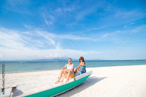 Happy honeymoon vacation at paradise. Couple relax on the white sand of beach, sitting in the old boat. Happy sea lifestyle. Young family, man and woman rest on the beach of ocean. Couple in love © belart84