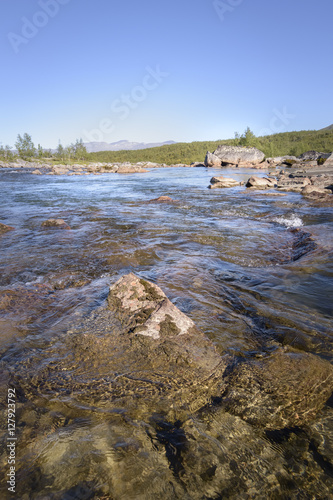 Beautiful clear and transparent water showing the rocks in the river with tranquil blue sky background photo