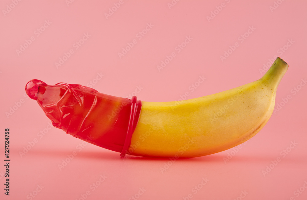 red condom and a banana - obrazy, fototapety, plakaty 