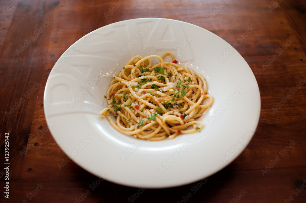 Close up view of the plate with italian styled spaghetti with parmesan, basil and dried tomatoes