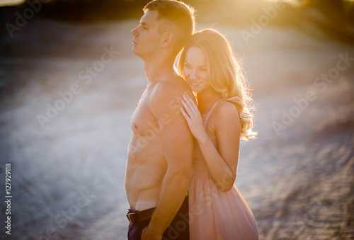 charming and young man and woman standing together on sand