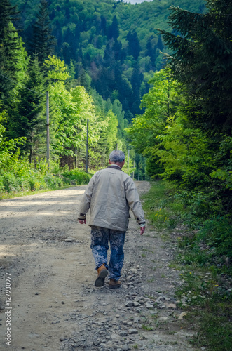 Senior man is going on the mountains road