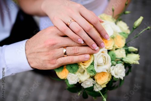 hands of the bride and groom on wedding bouquet