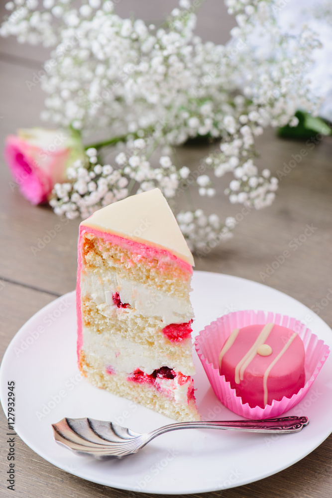 Homemade three layered cake with raspberry inside and pink candy on a white plate Homemade three layered cake with raspberry inside and pink candy on a white plate
