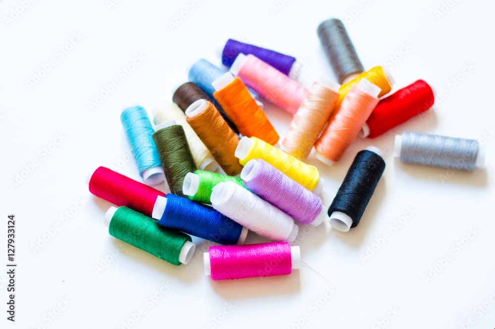 multicolored spools of thread on white background multicolored spools of thread on white background