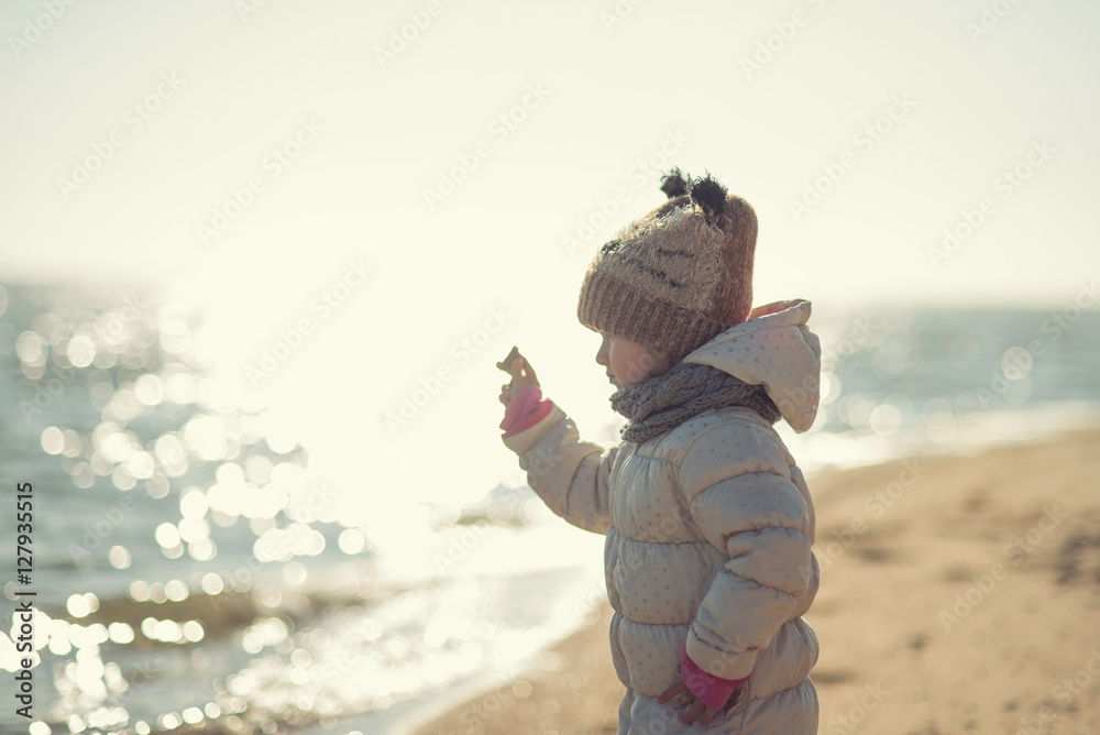 child walks on the beach at sunset in winter child walks on the beach at sunset in winter