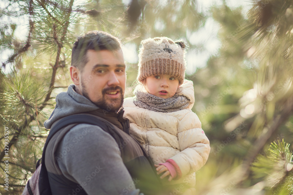 father holding a child walking in the park, walks in the pine forest