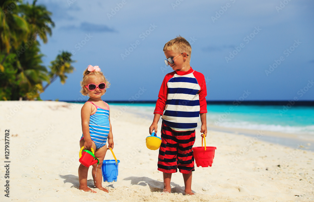 cute little boy and toddler girl play with sand on beach cute little boy and toddler girl play with sand on beach