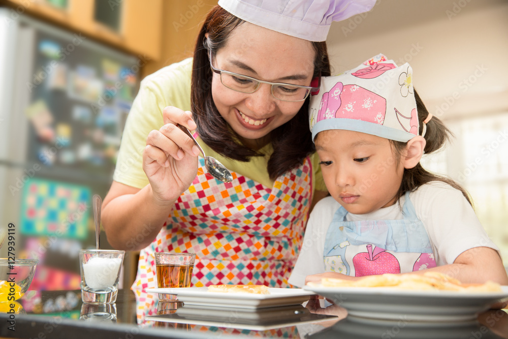 Asian mother and daughter enjoy making pancake in kitchen Asian mother and daughter enjoy making pancake in kitchen
