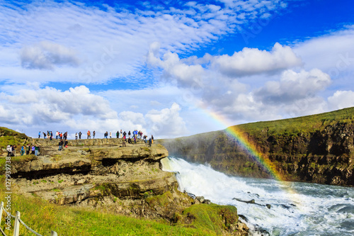 tourists watching rainbow on waterfall in Iceland